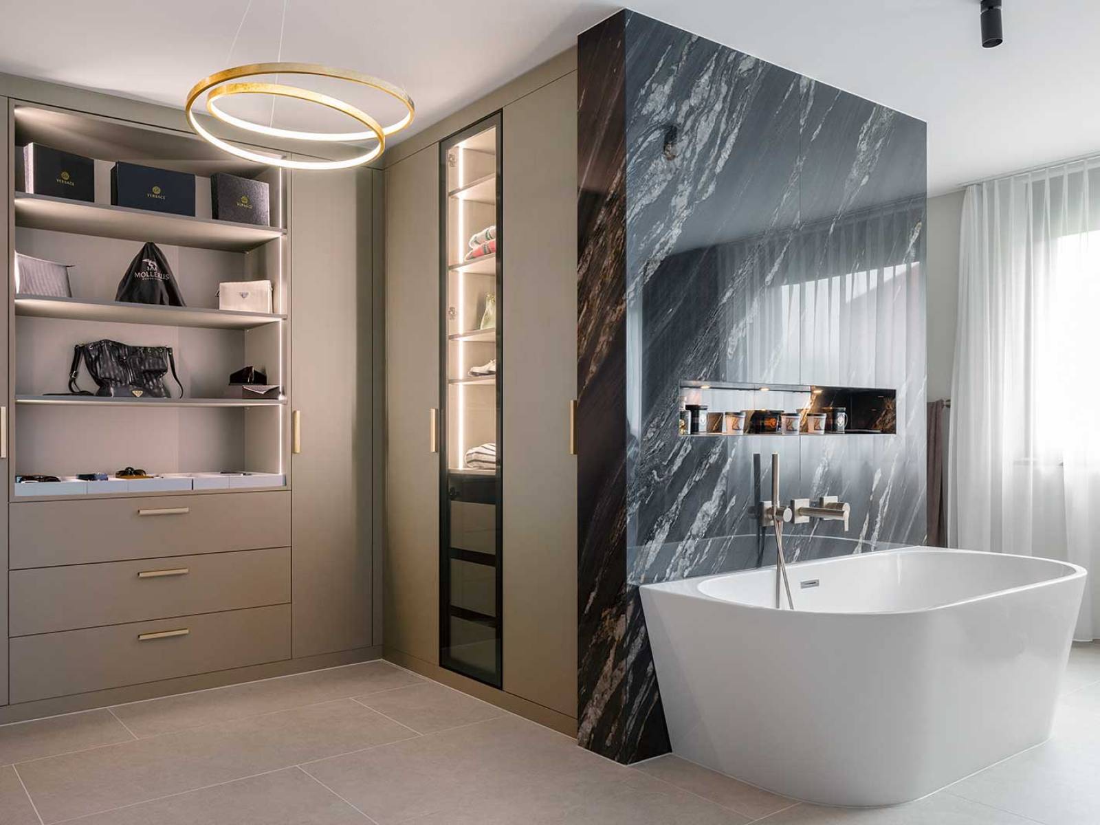 Vor einer Wand in dunkler Marmoroptik steht die freistehende Wanne, der angrenzende Ankleidebereich greift Materialität und Farbigkeit auf. Die Manufaktur aus der Ostschweiz plante den individuell abgestimmten Innenausbau. ELBAU.