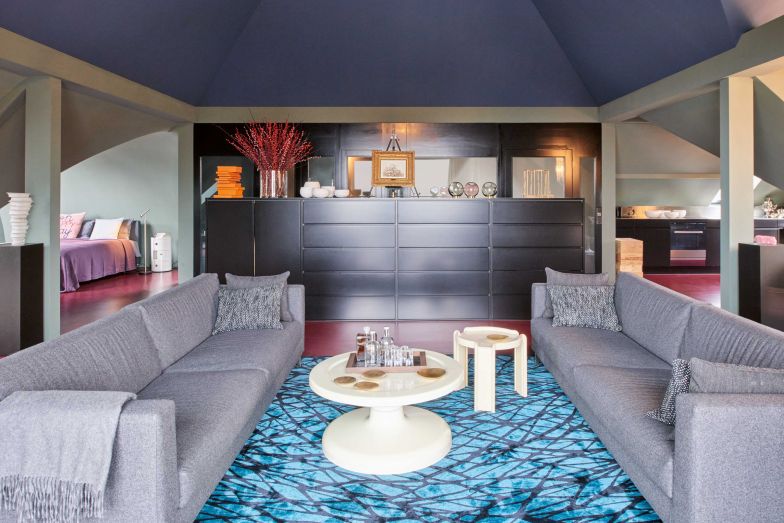 Wohnen mit Rückhalt: Optisch begrenzt das schwarze Sideboard den Wohnbereich gegen die Funktionszonen Eingang, Schlafen und Küche. Das ochsenblutrote Linoleum zieht sich durchs gesamte Loft, hier mit Teppich von Rug Star «Hotel Dresden», darauf Sofas «Lizard» von Friedemann Ramacher. Die Salontische sind Fundstücke, die Brände stammen von Manufaktor Hinteregg.