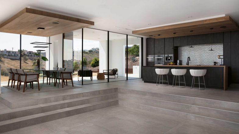 Die dunkle Küche bildet das Gegenstück zu den sonst sehr hellen Räumen. Ein gedeckter Aussensitzplatz lädt zum Essen im Freien ein. Foto: MBRGR Photography