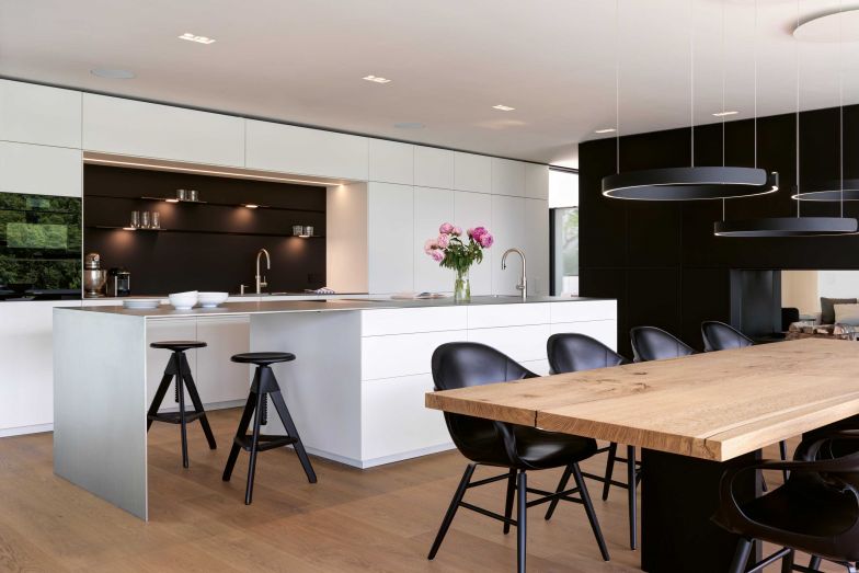 Die Küche fertigte das Unternehmen Orea im Muotathal. Besonders ist nicht nur die elektrifizierte Schiene in der Rückwand, sondern auch die L-förmige Arbeitspaltte im Ice-Design von Suter Inox. Leuchten & Lichttechnik: Occhio; Armaturen: Quooker; Küchengeräte: Miele; Herd: «Bora Professional 2.0.»