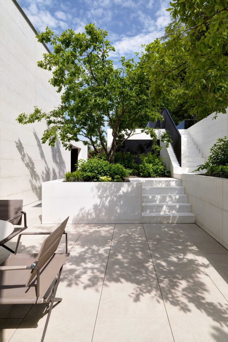 Der gefasste Hof an der Rückseite des Hauses ist eine Art Gegenstück zur Sonnenterrasse mit Infinity Pool. Der naturnah gestaltete Hang geht direkt in das Waldgrundstück über.