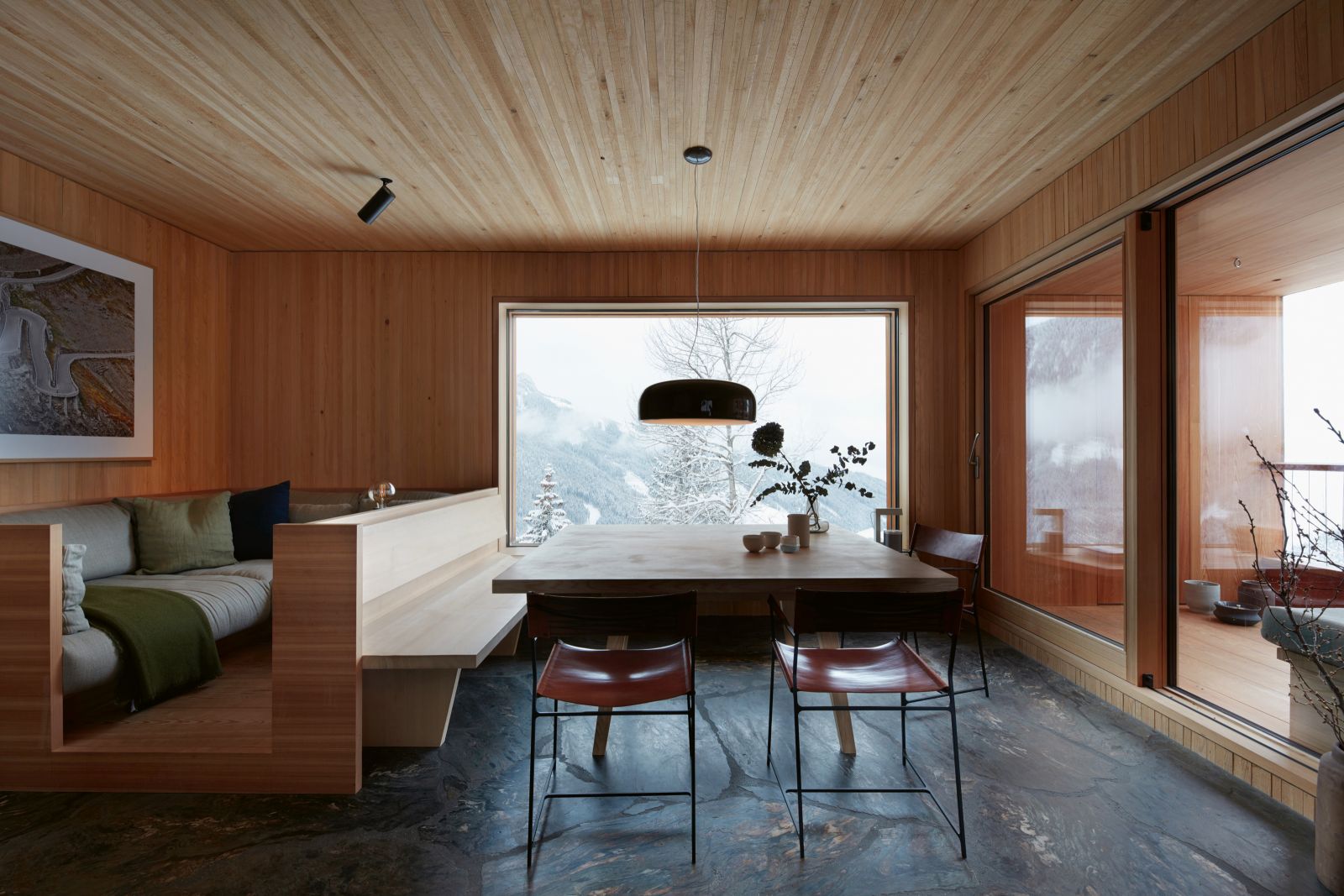 Wohnzimmer mit Lounge, Essbereich und Küche bilden einen offenen Raum, der geschickt aufgeteilt ist. Die windgeschützte Loggia ist eine von insgesamt drei in den oberen Stockwerken, die den ansonsten streng kubischen Baukörper gliedern und in alle Richtungen Aussenplätze hinzufügen. Pendelleuchte: «Smithfield» von Jasper Morrison für Flos; Esszimmerstühle: Klaus Lichtenegger.