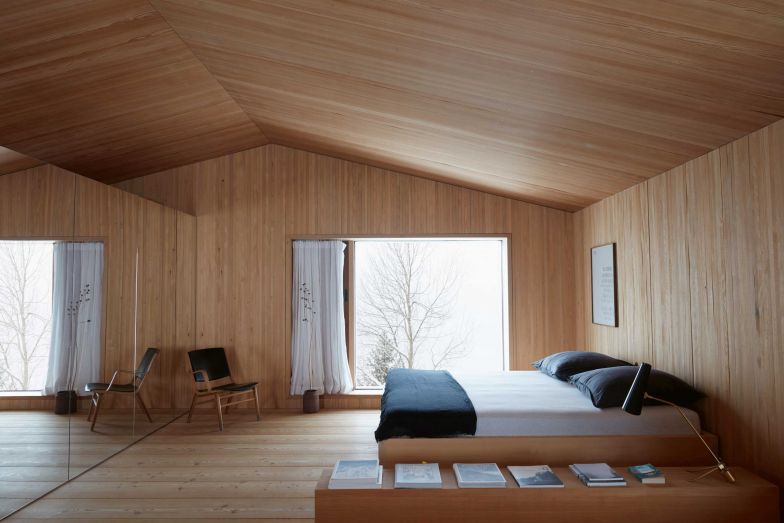 Die oberste Etage ist Arbeits- und Schlafbereich sowie Bibliothek und bietet Ausblicke in vier Richtungen. Hinter dem Stauraum mit den verspiegelten Türen befinden sich  Bad und Dampfbad. Die Tannenholzpaneele und die Lärchenholzdielen sorgen für eine minimalistische Ästhetik und verleihen dem Raum etwas Reines.