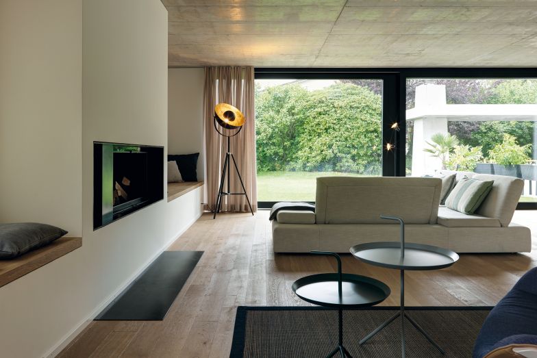 Parkettfussböden, weiss verputze Wände und Vollgeschossdecken aus Sichtbeton sorgen im gesamten Haus für ein freundliches und warmes Ambiente. Im geräumigen Wohnzimmer trägt zudem ein Kamin seinen Teil dazu bei. Die stilvollen Sitzmöbel im Haus stammen vom Zürcher Designladen «The Chair».