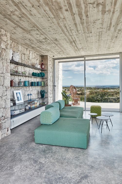 Auf dem Bücherregal in der Wandnische ist traditionelle Keramik Siziliens ausgestellt. Die drei Couchtische besitzen Lavasteinplatten und stammen vom Flohmarkt. Das Sofa «Ribbon» ist ein Entwurf von Claesson Koivisto Rune für Paola Lenti. Ebenfalls von Paola Lenti: Poufs «Picot».