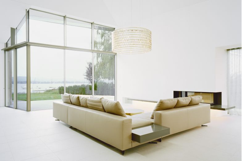 Das Zentrum des Hauses bildet der über zwei Geschosse reichende Wohnbereich mit Kamin. Das Sofa wie auch der Tisch von Minotti bringen italienisches Lebensgefühl an den Bodensee.