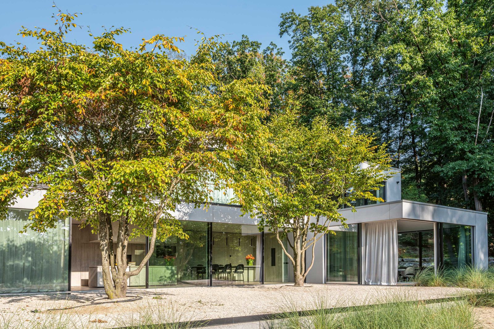 Die Villa wurde behutsam in ein Waldgrundstück eingebettet. Die Bäume spenden im Sommer auch den Schlafzimmern im Obergeschoss Schatten – und schützen vor allem die Terrasse des Master-Bedrooms vor Einblicken.