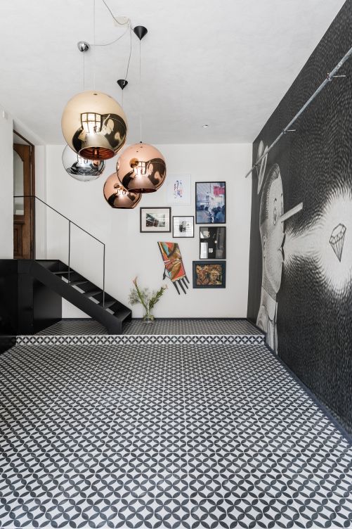 Ihr Mann hätte hier gern eine Garage gehabt, aber Anne-Sophie Hollenwäger konnte sich mit der Idee vom Eingangsbereich durchsetzen. Das Türblatt oberhalb der Treppe war eines der wenigen alten Dinge, die der Bauherrschaft erhaltenswert schienen. Pendelleuchten «Copper Bronze» von Tom Dixon.