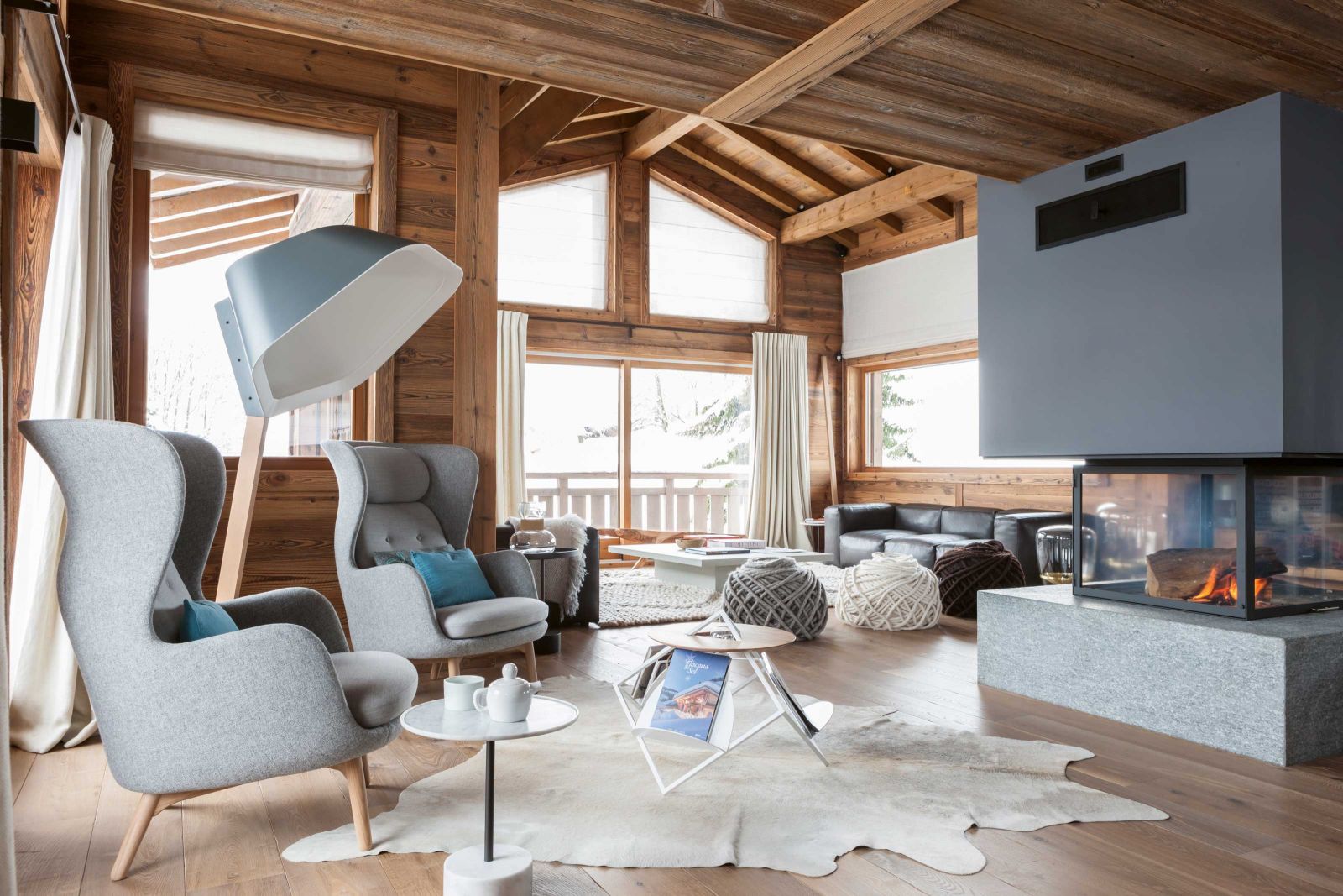 Mit der hohen Decke wirkt das Wohnzimmer wie das Mittelschiff einer Kirche. Ein Kamin markiert die Mitte des lichten Raumes und sorgt für Geselligkeit. Die Sessel «Ro» hat Jaime Hayon für Fritz Hansen entworfen; die nicht weniger markante Stehleuchte namens «Peye» stammt aus der Feder von Numéro 111 für Ligne Roset. Tisch «Lighbrary» von Mickael Koska brachte Eigentümer und Interior Designerin zusammen.