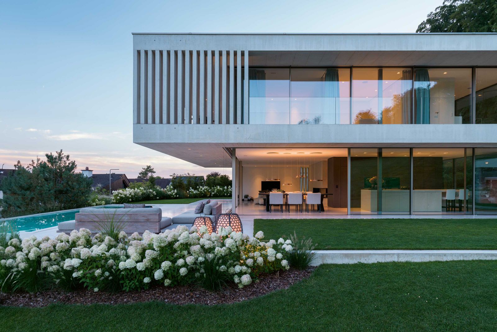 Die schwellenlose Schiebeverglasung von Sky-Frame lässt sich an der Ecke zum Pool komplett öffnen und schafft so eine harmonische Verbindung zwischen innen und aussen.