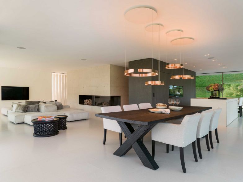 Keine unnötigen Wände: Der Betonkern, in dem sich ein Gäste-WC, ein Reduit und der Kaminabzug verstecken, gliedert zusammen mit dem Küchenmodul das Erdgeschoss. Im Eingangsbereich schliesst hier die Treppe ins Obergeschoss an. Pendelleuchten: Occhio.