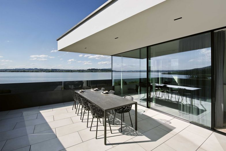 Die von Robby und Francesca Cantarutti für Fast entworfenen Aluminium-Sessel «Forest» mit ihrer verästelten Struktur der Sitzschale gruppierte das Ehepaar um den Esstisch. Von der Terrasse im Obergeschoss bietet sich ein traumhafter Blick auf den oberen Zürichsee.