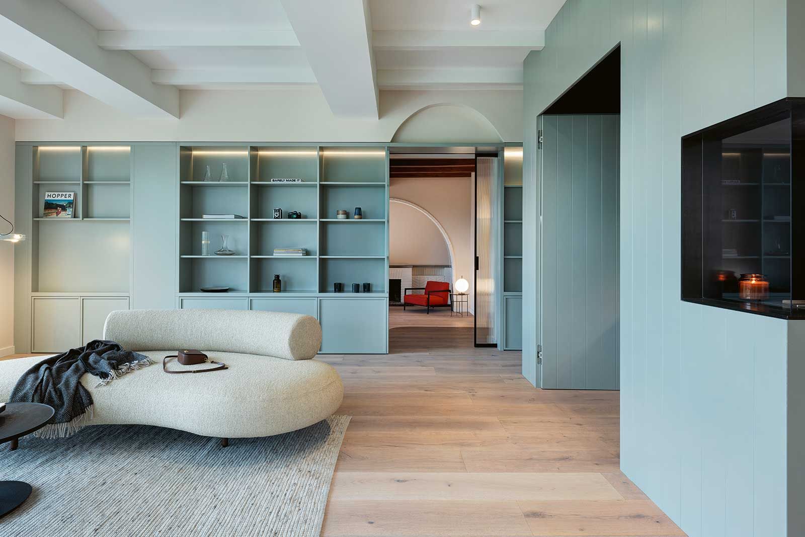 Der gezielte Rückbau einzelner tragender ­Wände ermöglichte eine neue Raumorganisation mit offenen, lichtdurchfluteten Bereichen. Innenarchitektonische ­Details zitieren den historischen Art déco-Stil der Villa, etwa durch elegant ­geschwungene Rundbögen oder die streng geometrische Gliederung des massgefertigten Bücherregals, der Küchenmöbel und Glastüren.