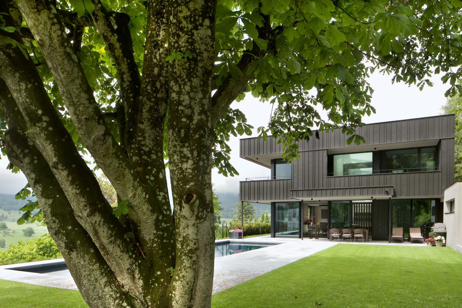 Den Holzrahmenbau umschliesst eine Hülle aus dunklem Zink. Grosszügig dimensioniert besitzt das Haus jede Menge Freiräume bis in den Garten hinein.