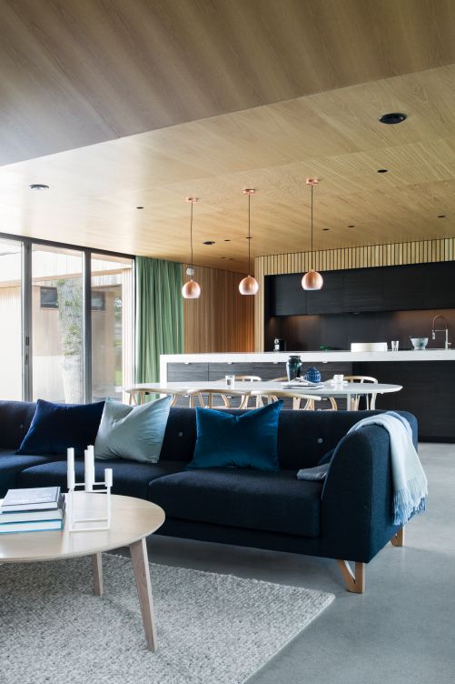 Über dem Esstisch hängt gleich dreimal die Pendelleuchte «Ball» von Frandsen in matt gebürstetem Kupfer, während die Küche von eingebauten Scheinwerfern beleuchtet wird. Am Esstisch: «Wishbone Chair» von Hans J. Wegner für Carl Hansen & Søn; Teppich «Peas» von Hay; Sofatisch von Bohus.