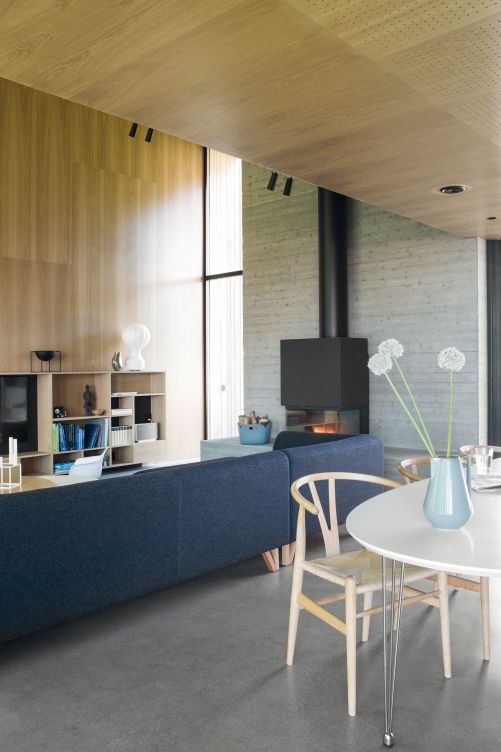 Ein grosser Kamin heizt den geräumigen Wohnraum zusätzlich zur Fussbodenheizung im ganzen Haus. Die Regale sind ein Entwurf des Architekten und wurden vor Ort gebaut. Auf ihnen stehen die Schale «Kubus» von By Lassen, eine Vase von Georg Jensen sowie die Tischleuchte «Gatto» von Achille und Pier Castiglioni für Flos.