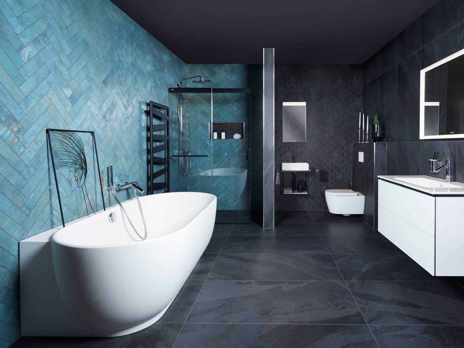 Die edlen Wandplatten in Smaragdgrün laden zum Verweilen im Wannenbad ein. Der Übergang von schwarzen grossformatigen Keramikplatten zum kleineren Polygonformat verleiht dem Raum zusätzliche Tiefe. SABAG.