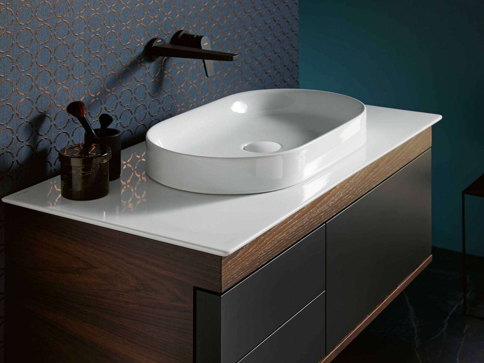 Für die Waschtische «Logica Plus» ist die aufein-ander abgestimmte Geometrie des breiten oberen Frontabschlusses mit den darunter liegenden Elementen bezeichnend. Der Korpus ist lackiert oder in Echtholz furniert erhältlich, die Front ist immer lackiert. Das Modell mit Schubladen kann nur mit einem Aufsatzwaschbecken kombiniert werden. SANITAS TROESCH.