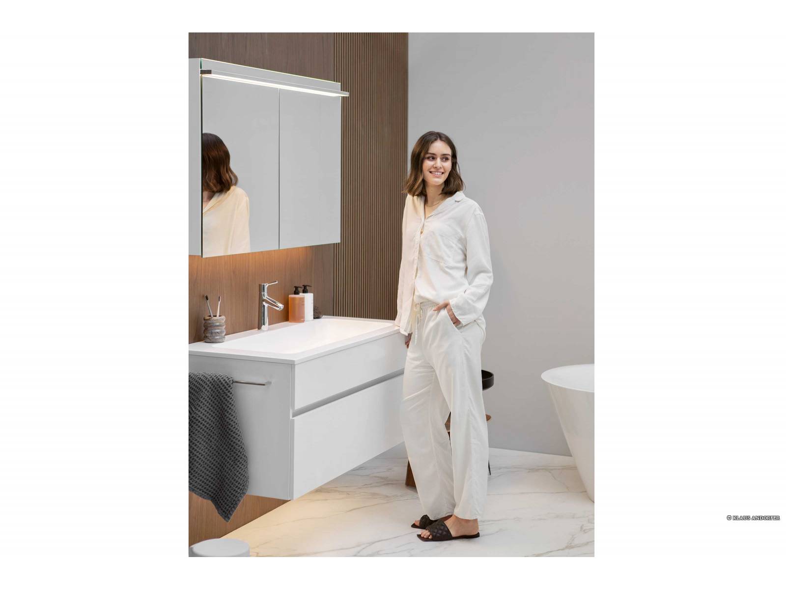 Vor der Wandverkleidung aus Wallnussdekor macht sich das zeitlose Design des Waschtischs «Lima» besonders gut. Der zweitürige Spiegelschrank ist mit hochmoderner LED-Beleuchtungstechnologie ausgestattet. Sie sorgt dafür, dass das Bild im Spiegel perfekt reflektiert wird und der Raum optimal beleuchtet ist. DIPL. ING. FUST.