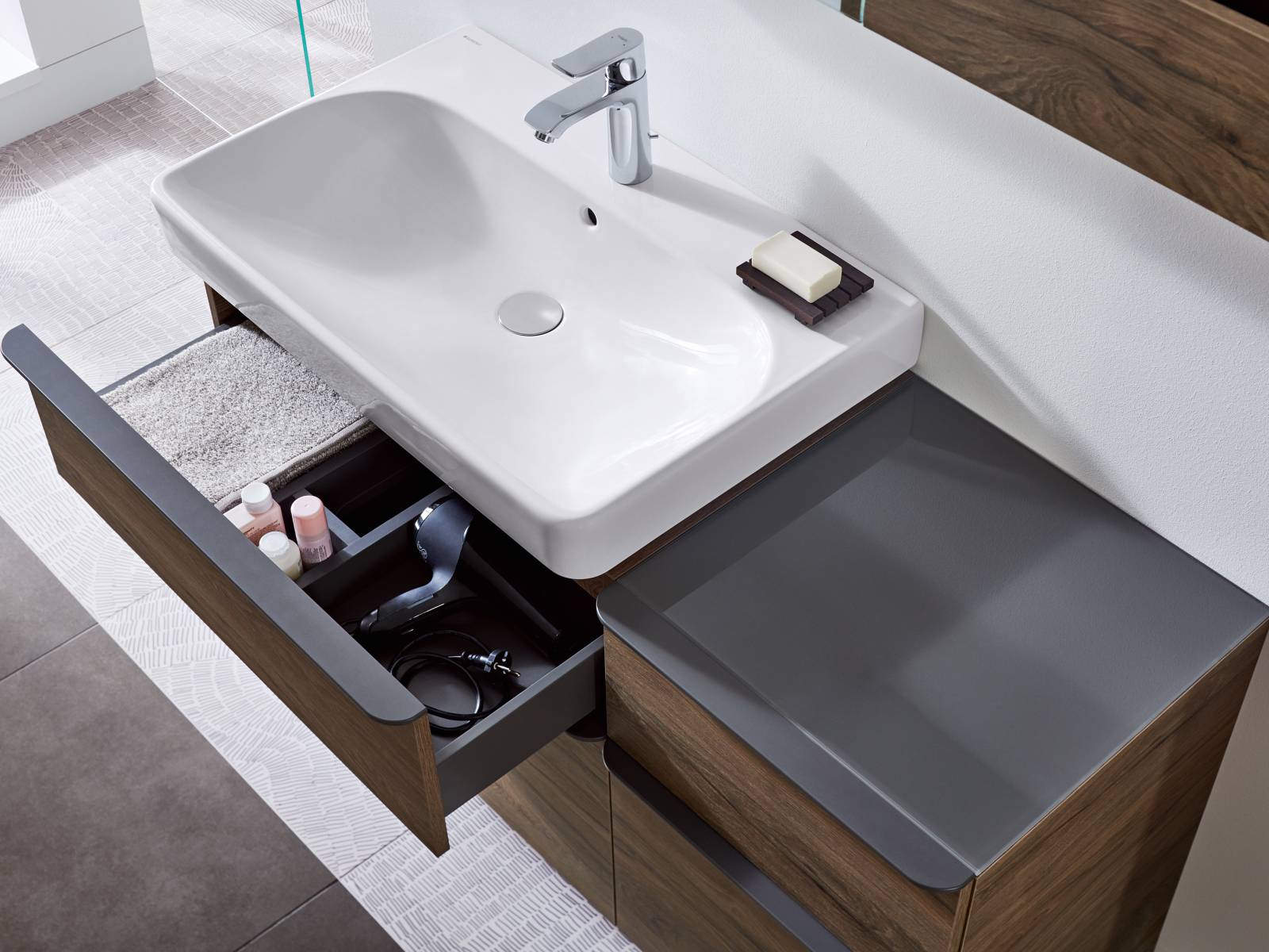 Das Badprogramm One gibt sich ausserordentlich aufgeräumt: Unschöne Teile wie Anschlüsse und Siphon verschwinden in der Vorwandinstallation und werden von einer Blende verdeckt. Zur Kollektion gehören ein Waschtisch, freischwebend oder mit Unterschrank, eine Wandarmatur, ein wandintegrierter Spiegelschrank und ein Wandablauf für die Dusche sowie eine Ablagebox. Geberit.