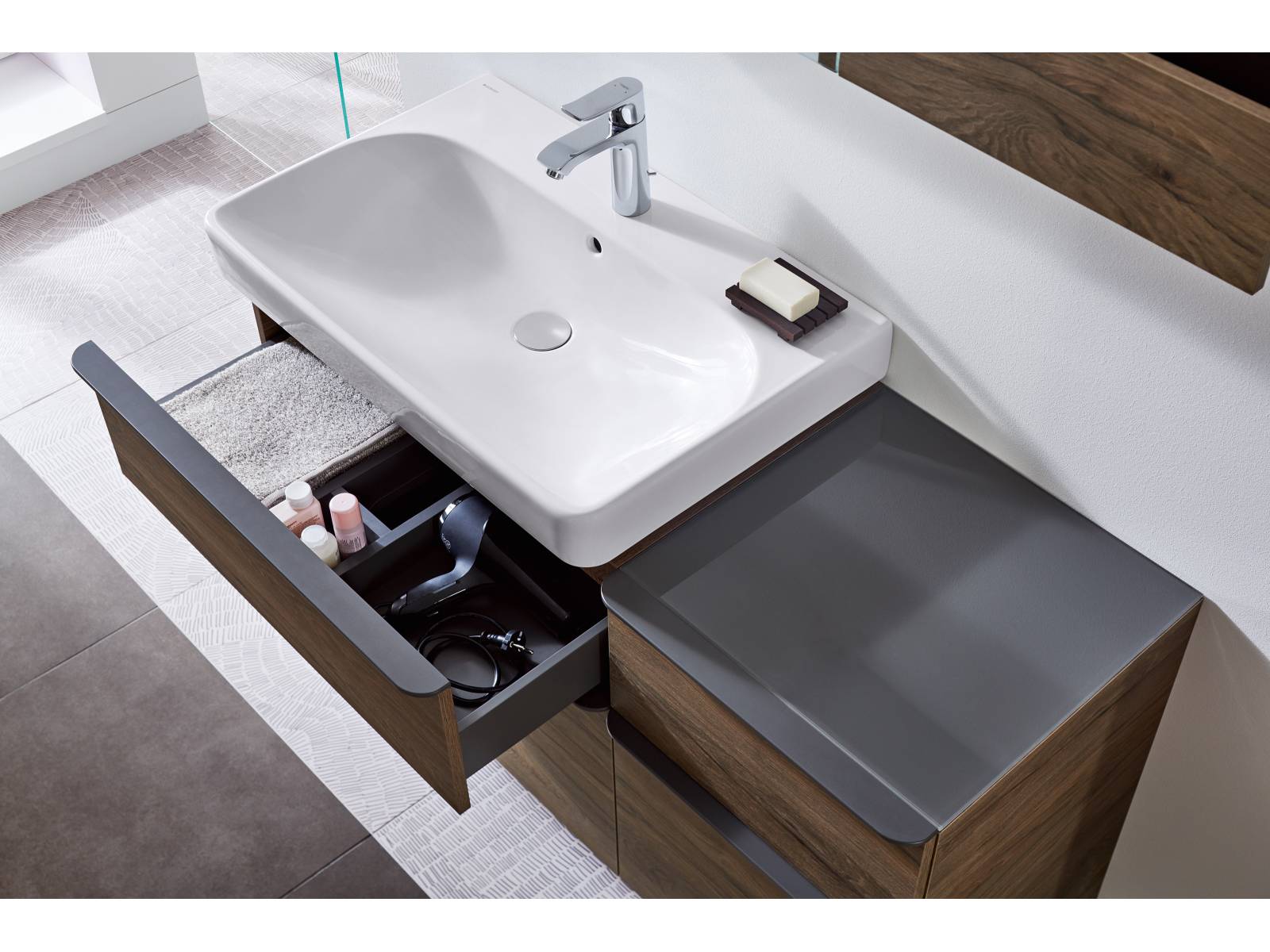 Das Badprogramm One gibt sich ausserordentlich aufgeräumt: Unschöne Teile wie Anschlüsse und Siphon verschwinden in der Vorwandinstallation und werden von einer Blende verdeckt. Zur Kollektion gehören ein Waschtisch, freischwebend oder mit Unterschrank, eine Wandarmatur, ein wandintegrierter Spiegelschrank und ein Wandablauf für die Dusche sowie eine Ablagebox. Geberit.