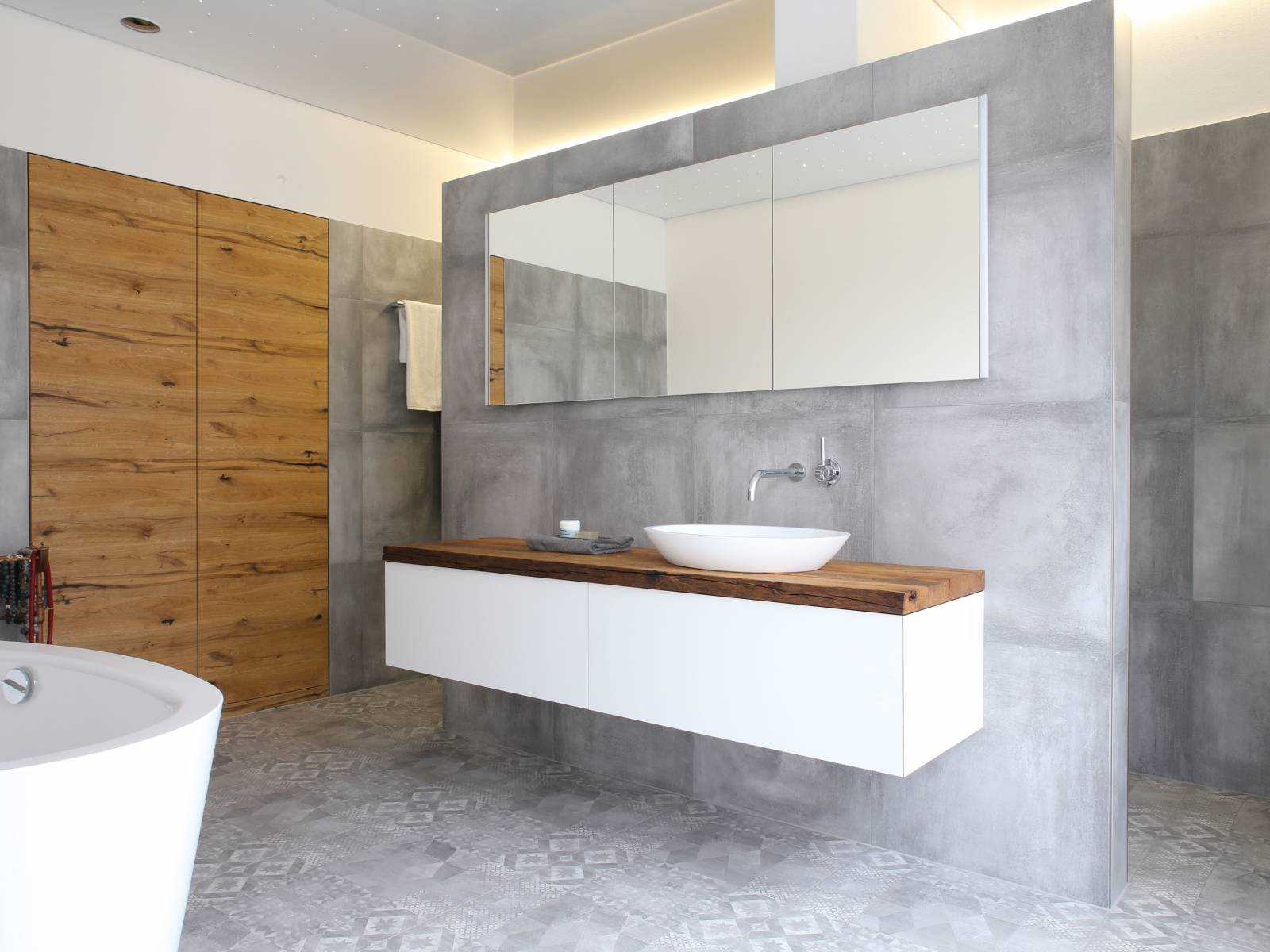 Alt und neu gekonnt kombiniert: Auf dem wandhängenden Möbel mit der Massivholzabdeckung in Altholz macht sich das schlichte Aufsatzwaschbecken besonders gut. Loosli.