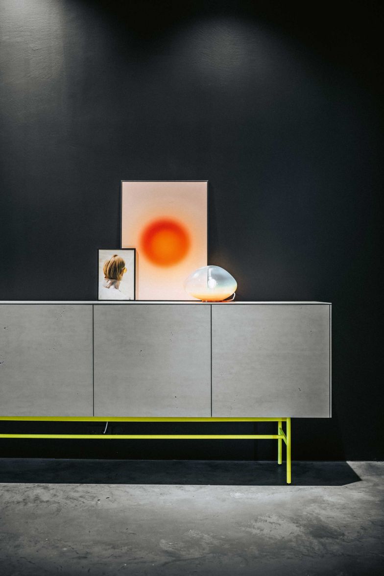«Soma» – ein System, mehrere Stile: Als Highboard der «Soma Edition» in Lack Messing, als rubinfarbenes Sideboard mit leuchtrotem Untergestell oder als Sideboard mit einer Betonoberfläche, die erst diesen Herbst präsentiert wurde. Foto: Ingo Rack. 