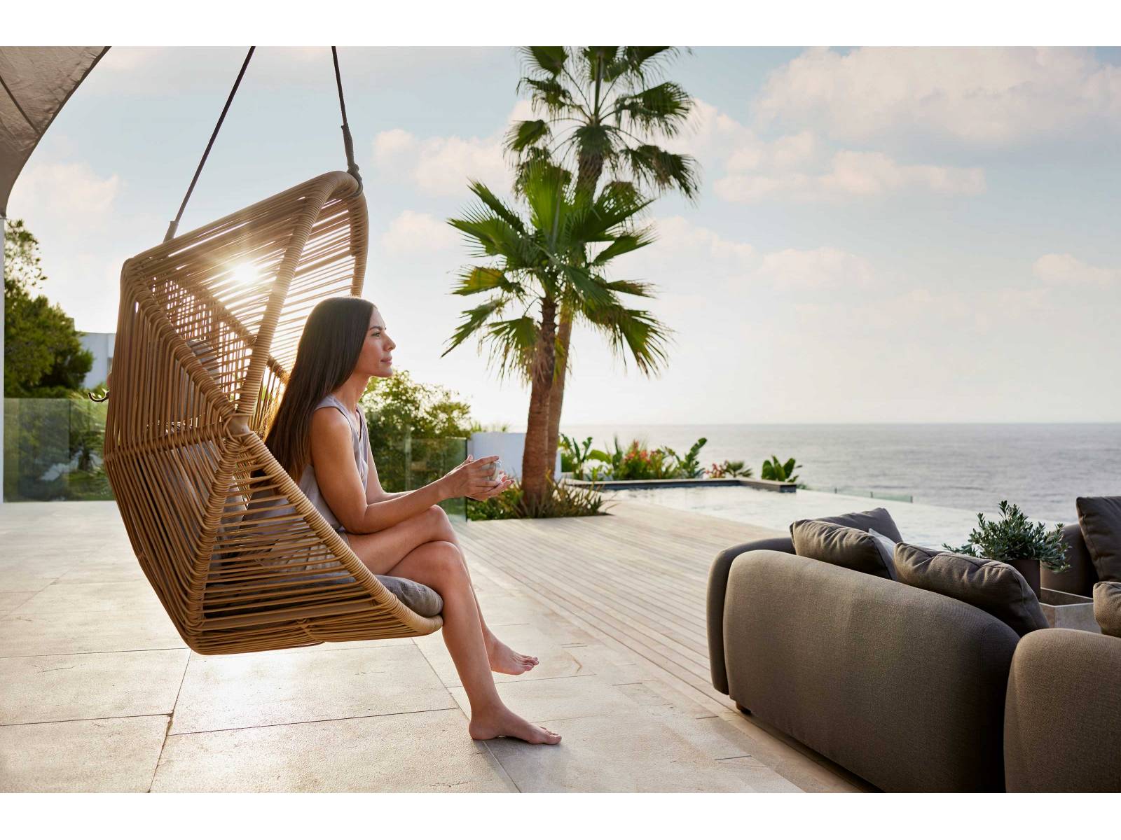 Im Hängesessel «Hive» fängt der Tag nicht nur gut an, er hört auch gut auf. Wie man die Zeit dazwischen gestaltet, dürfte bei diesem Ausblick nicht die Frage sein. Wer keine Möglichkeit hat, den Sessel aufzuhängen, kann ihn auch auf einem Gestell aus Teakholz oder Aluminium platzieren. In Natur oder Grün. Design: Foersom &amp; Hiort-Lorenzen. CANE-LINE.