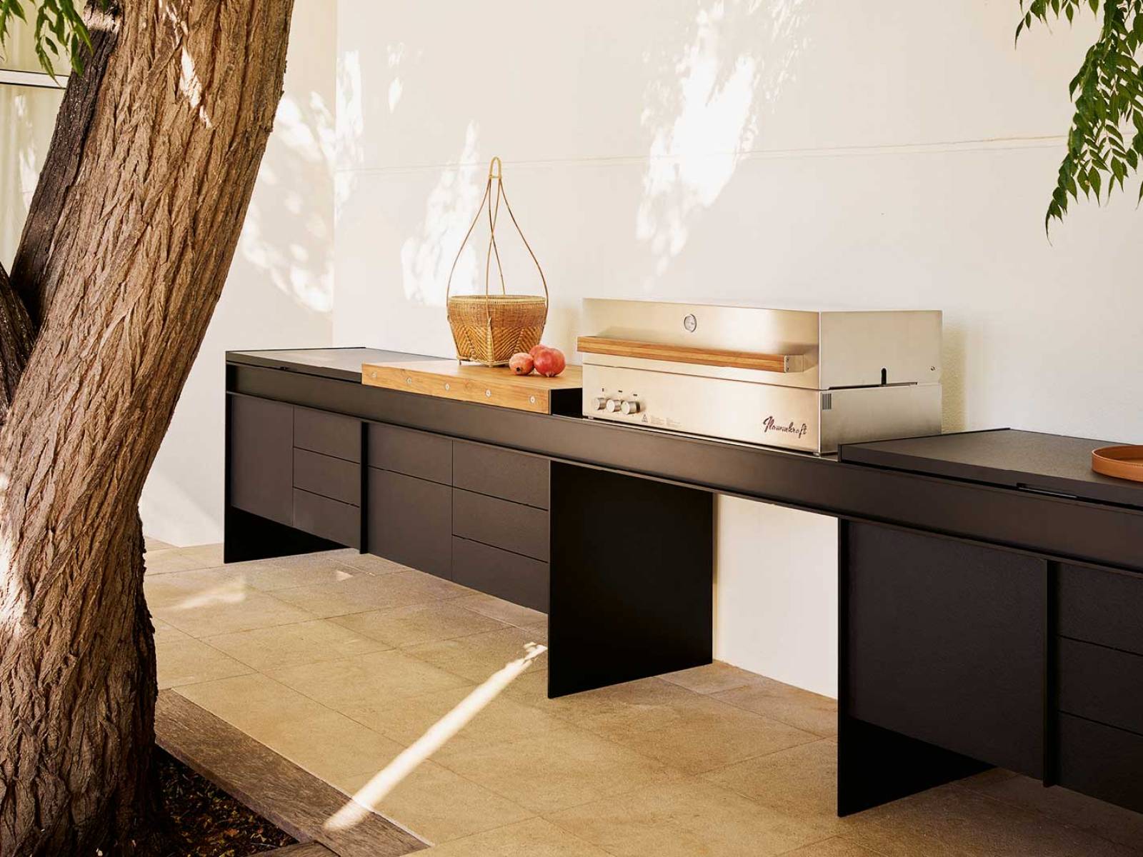 Die erste Outdoor-Küche des italienischen Herstellers besticht durch ihre schwebende Ästhetik. Diese wird durch eine raffinierte Brückenstruktur aus mattschwarz lackiertem Aluminium erzeugt, an der die Aufbewahrungselemente scheinbar schwerelos hängen. Poliform.