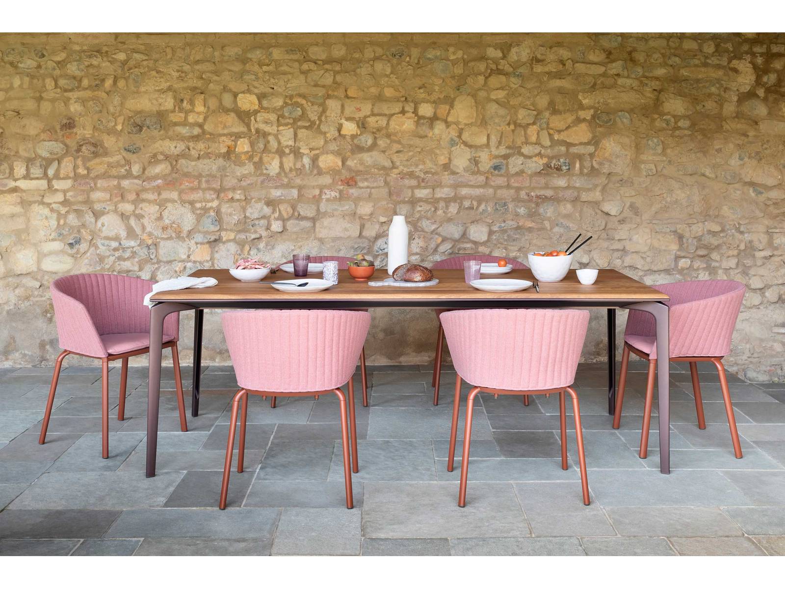 Spezielle wasserabweisende Öle schützen die grazile Tischplatte aus afrikanischem Iroko-Holz, deren honiggelber Farbton besonders einladend wirkt. Zur Seite steht ihr die neue Ausführung des Armstuhls «Ria», der sich mit Kissen und gesteppter Rückenlehne sehr angenehm besitzt. FAST.