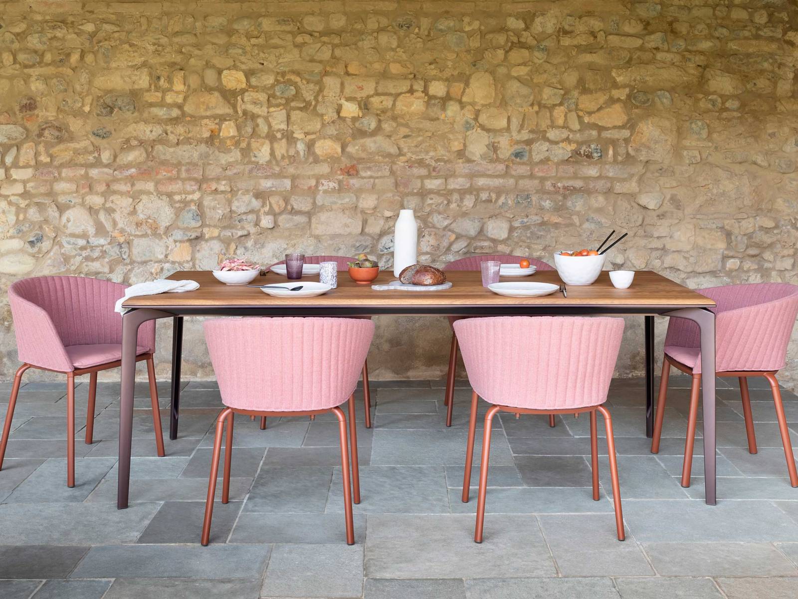 Spezielle wasserabweisende Öle schützen die grazile Tischplatte aus afrikanischem Iroko-Holz, deren honiggelber Farbton besonders einladend wirkt. Zur Seite steht ihr die neue Ausführung des Armstuhls «Ria», der sich mit Kissen und gesteppter Rückenlehne sehr angenehm besitzt. FAST.