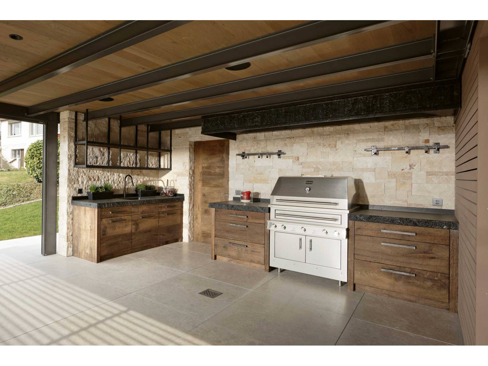 Warum sich mit einem einfachen Grill zufrieden geben, wenn man auch Platz für eine Outdoorküche hat? Diese ist eine Spezialanfertigung aus Eiche und mit einem Edel-Grill von Kalamazoo ausgestattet. Praktisch: Wer das Chili-Knoblauchsalz fürs Grillgut sucht, muss nicht vom Garten in die Küche rennen, sondern nur die Schublade aufziehen. ZBÄREN.