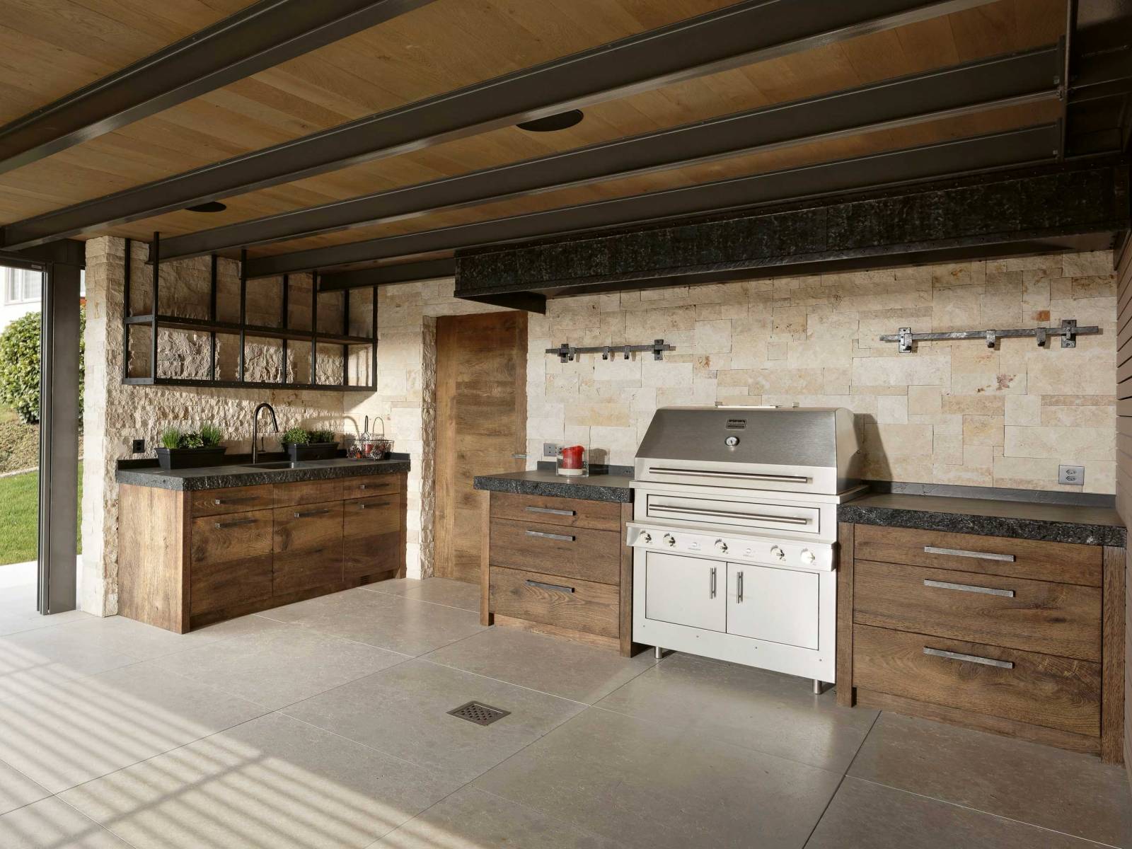 Warum sich mit einem einfachen Grill zufrieden geben, wenn man auch Platz für eine Outdoorküche hat? Diese ist eine Spezialanfertigung aus Eiche und mit einem Edel-Grill von Kalamazoo ausgestattet. Praktisch: Wer das Chili-Knoblauchsalz fürs Grillgut sucht, muss nicht vom Garten in die Küche rennen, sondern nur die Schublade aufziehen. ZBÄREN.