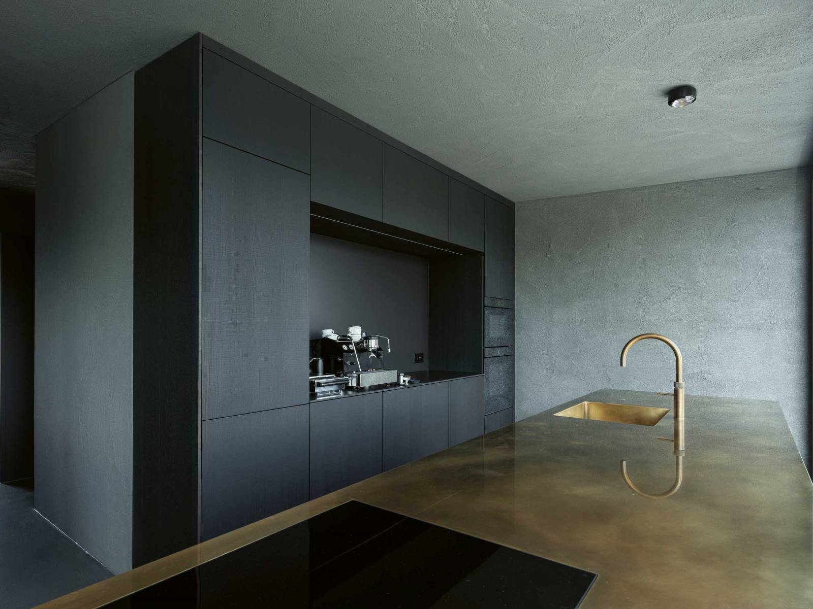 Wer im Muotathal produziert, kann nicht nur einzelne Küchenmöbel, sondern ganze Wohnkonzepte anbieten. In diesem Neubau verbergen sich hinter geräucherten Eichenfronten nicht nur Geräte und Geschirr, sondern auch viel Stauraum im Eingangs- oder Wohnbereich. Die Armatur in edlem Messing Patina liefert kaltes und kochendes Wasser. OREA / QUOOKER.