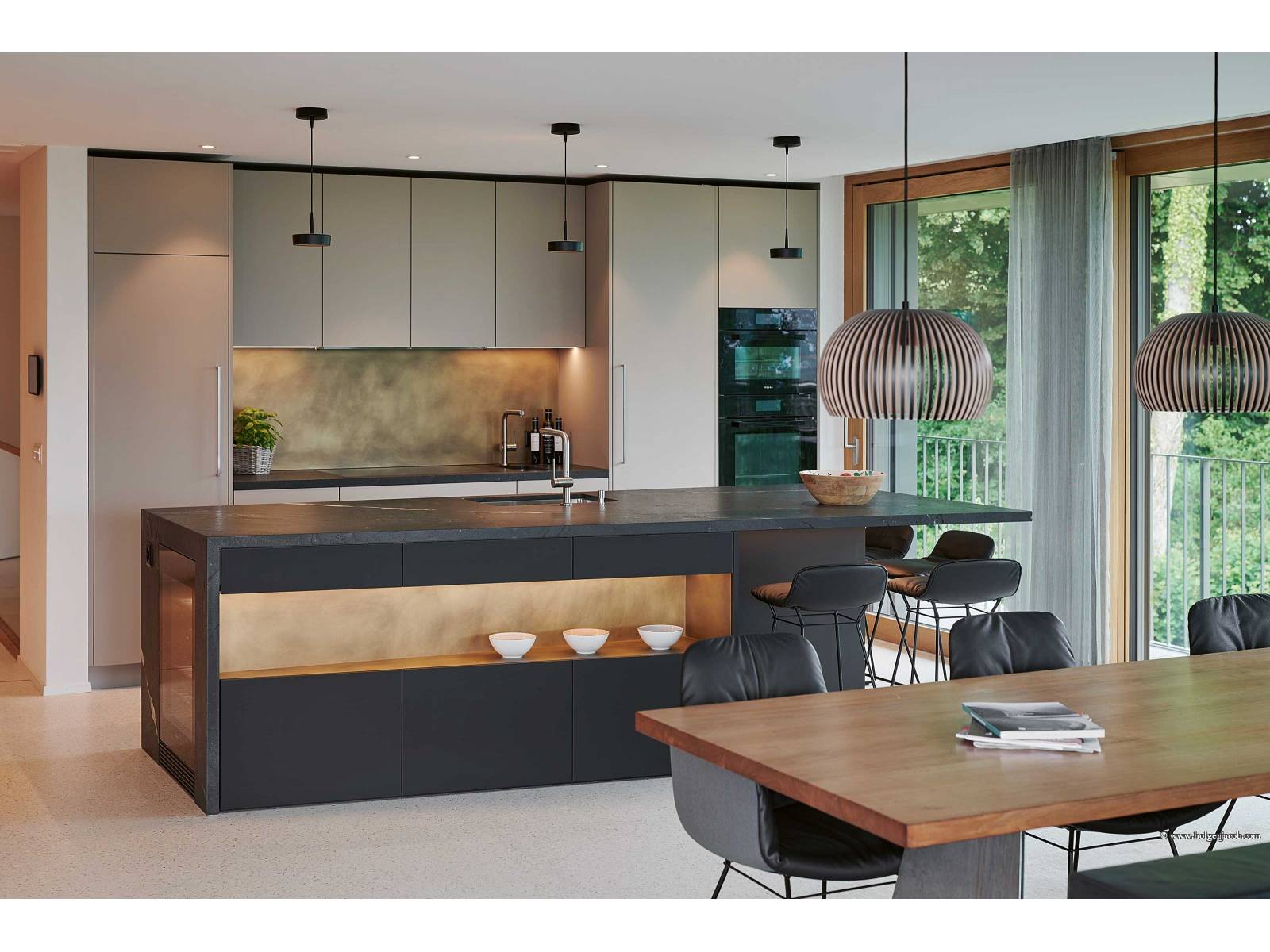 Hello Darkness: Schwarz hat längst auch die Küche erobert. Hier als stylische Kochinsel, der naturgrau gehaltene Hochschränke beistehen. Als verbindendes Element dienen die Nischen aus Messing. Ein weiteres Highlight ist die Arbeitsplatte aus Naturstein, deren Oberfläche den Eindruck von Leder erweckt. BRUNNER KÜCHEN.