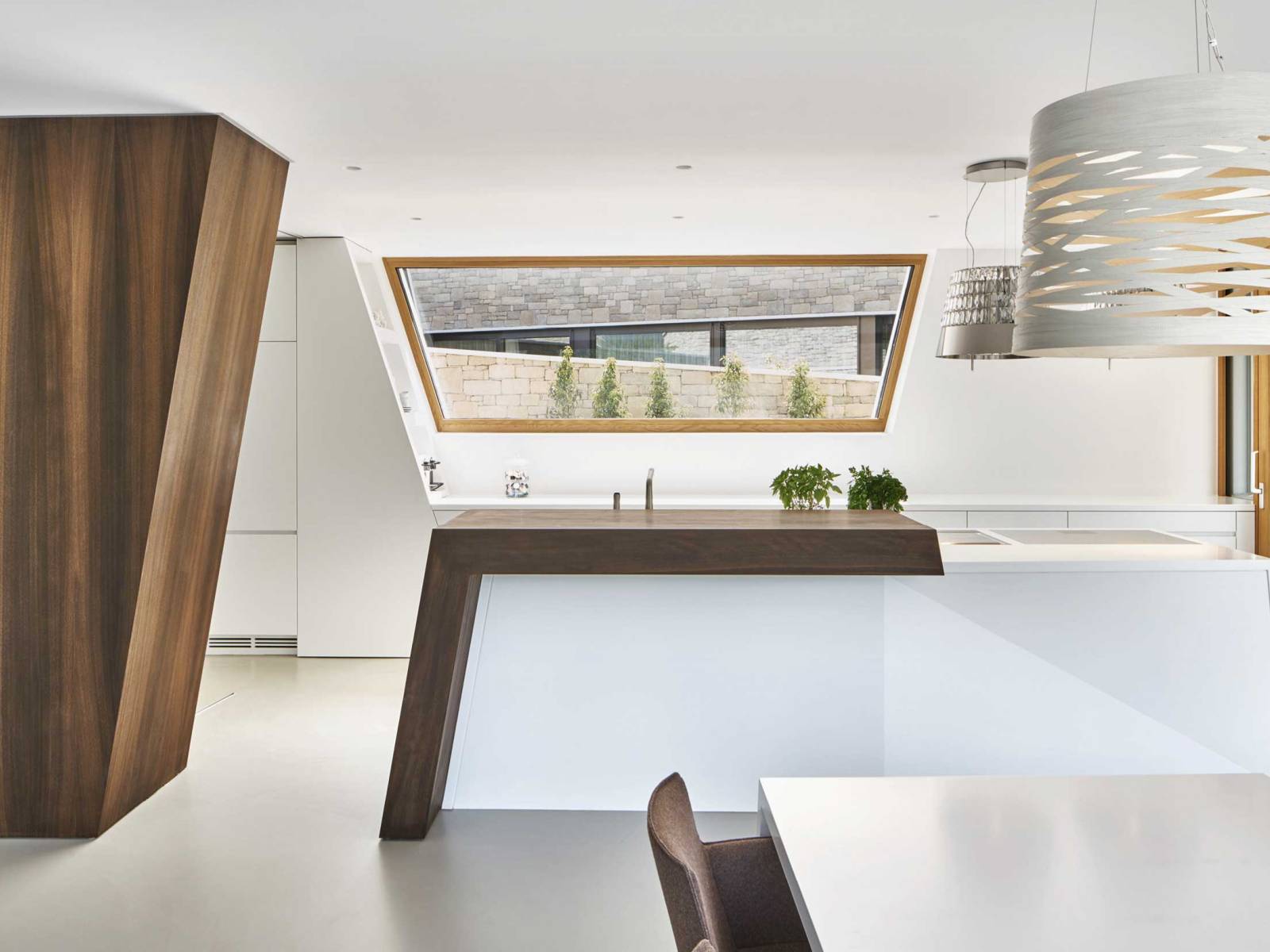 Die einzelnen Küchenelemente von «Coloralaccato», die in unterschiedlichen Winkeln angeordnet sind, erzeugen Spannung, aber auch schlichte Eleganz. Die kraftvolle Inszenierung wird durch das Aufeinandertreffen von naturbelassener Räuchereiche, weissen Lackfronten und der farblich abgestimmten Mineralabdeckung verstärkt. MOVANORM.