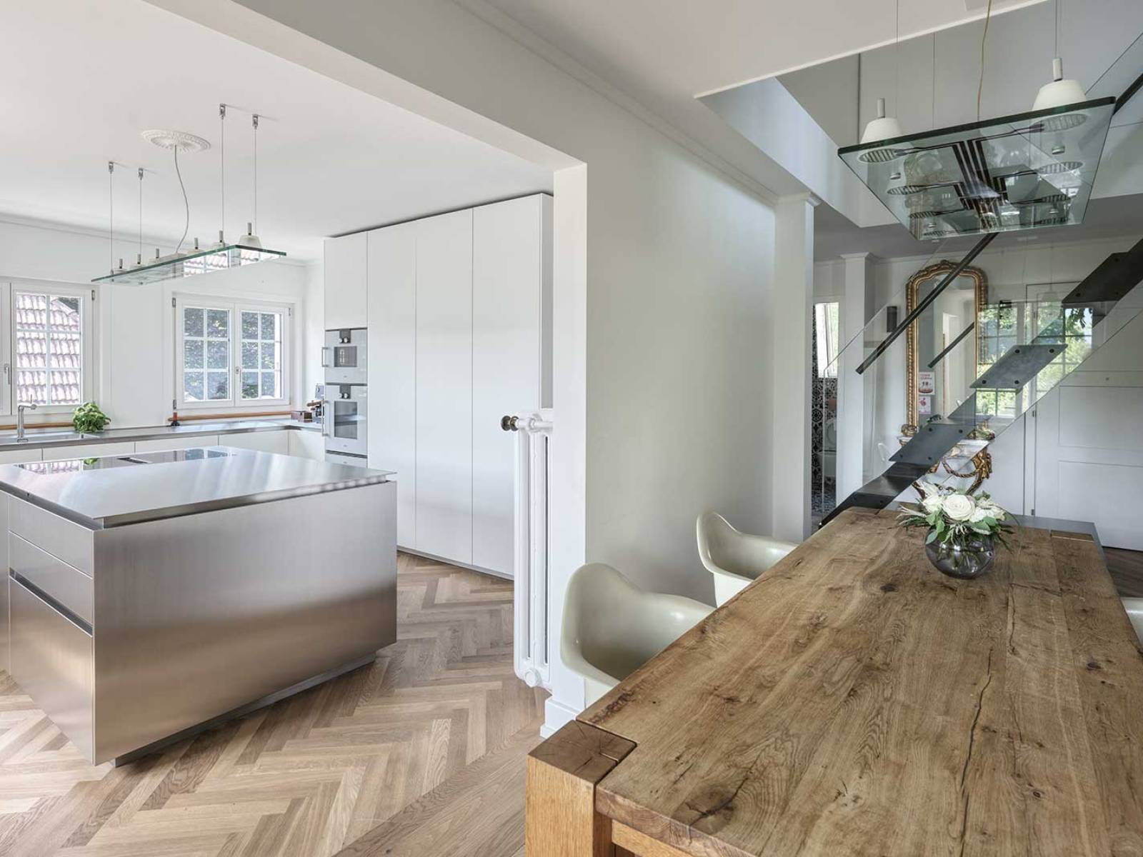 Diese Küche lebt von puristischer Präzision. Raum­hohe Schränke bilden den ruhigen Hintergrund zur ­markanten Edelstahlinsel, deren grosszügiges Kochfeld mit Muldenlüftung genug Platz für das Mise en place lässt. Edelstahl erstreckt sich flächendeckend über die ­Küchenzeile und integriert nahtlos Spüle mit Kräuter­garten. Hochwertige Geräte gewährleisten makellose Funktionalität in heller, offener Raumgestaltung. Foto André Herger. OREA.