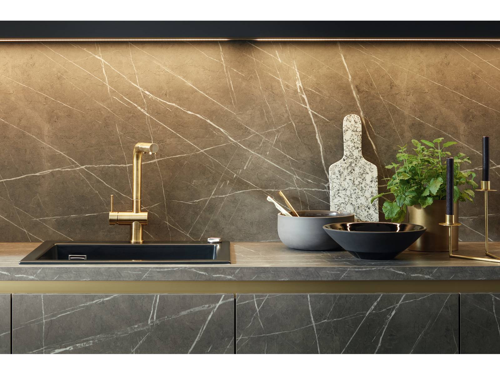 Zeitlos und dennoch topaktuell sind die eleganten Oberflächen aus der Targa-Linie, hier in dunklem Marmordekor, die durch ihre feine Maserung einen exklusiven Kontrast zu den edlen Messingdetails setzen. Schüller.