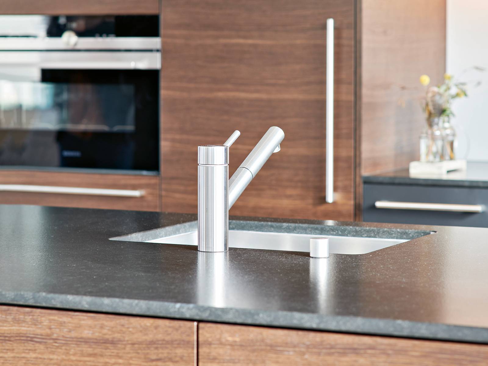 Der Küchenhersteller aus Bettwil baut Unikate auf Mass, die bis ins kleinste Detail durchdacht sind. In diesem Beispiel bestechen furnierte Fronten in Räucher-eiche mit einer Abdeckung aus satiniertem Granit. Brunner Küchen.