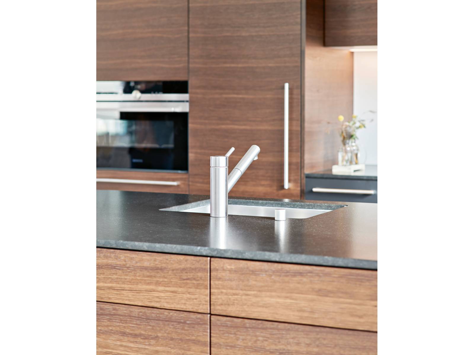 Der Küchenhersteller aus Bettwil baut Unikate auf Mass, die bis ins kleinste Detail durchdacht sind. In diesem Beispiel bestechen furnierte Fronten in Räucher-eiche mit einer Abdeckung aus satiniertem Granit. Brunner Küchen.