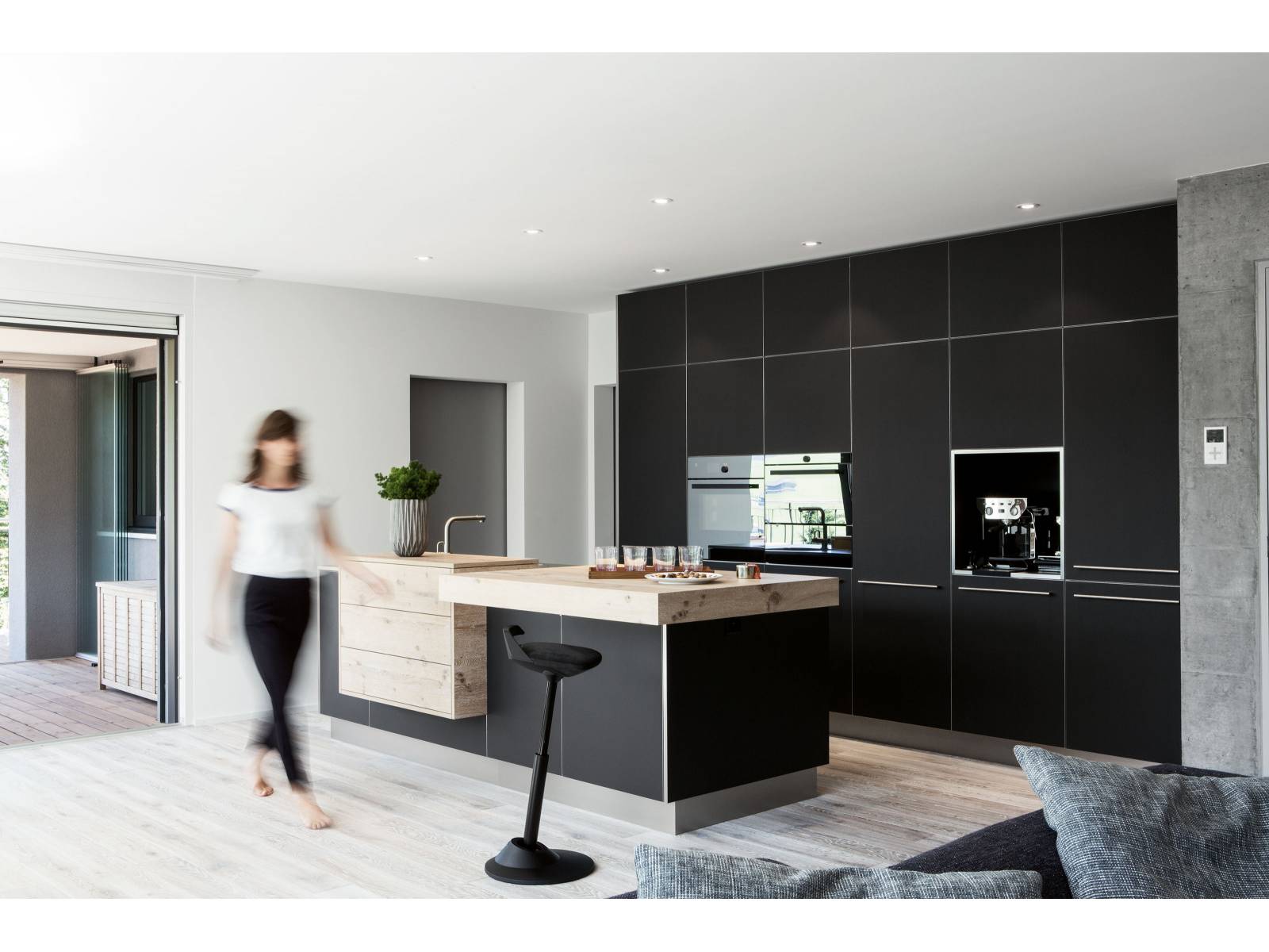 Gekalktes Eichenholz, Fronten aus schwarzem Linoleum und Arbeitsflächen aus Chromstahl finden sich hier zu einem harmonischen Ganzen zusammen und fügen sich nahtlos in den Wohnraum ein. Elbau.