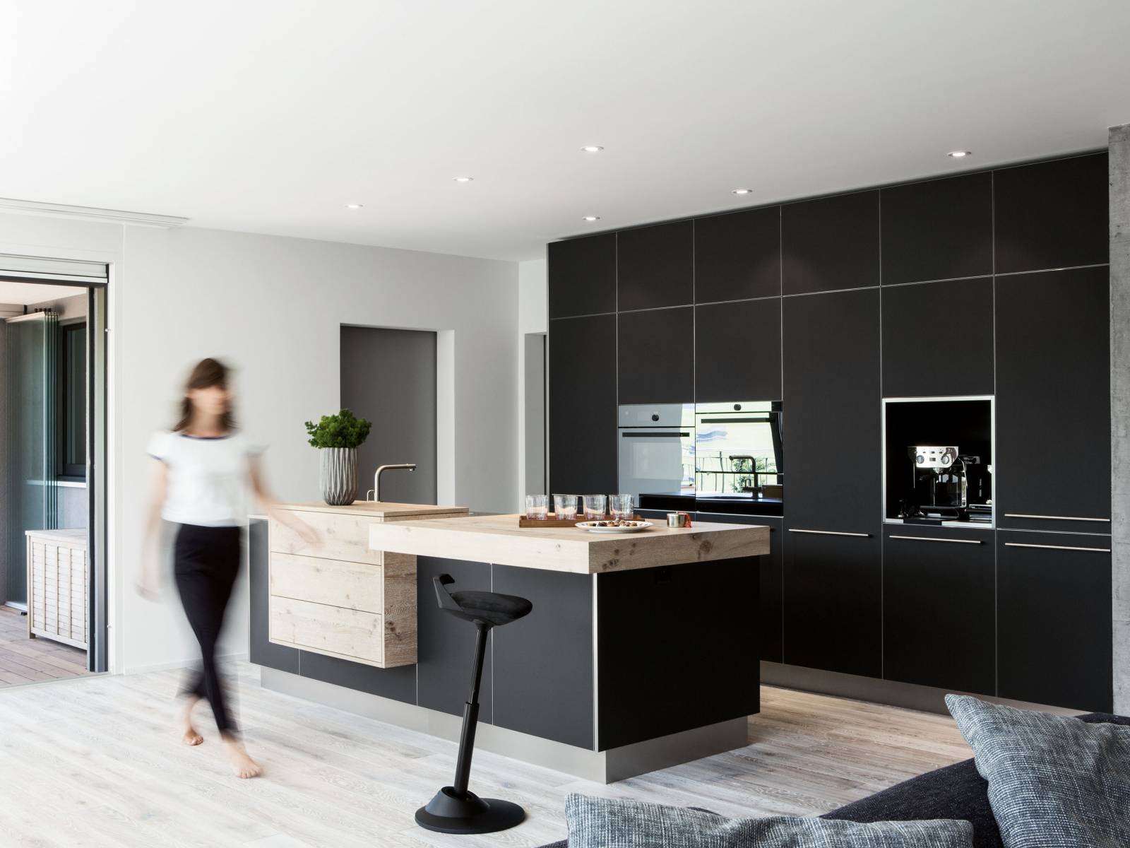 Gekalktes Eichenholz, Fronten aus schwarzem Linoleum und Arbeitsflächen aus Chromstahl finden sich hier zu einem harmonischen Ganzen zusammen und fügen sich nahtlos in den Wohnraum ein. Elbau.
