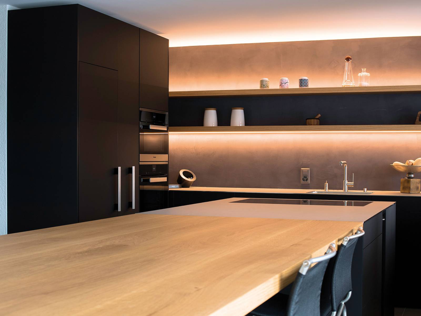 Holz, Rohmetall und Edelstahl sind die Hauptelemente für diese Küche. Stimmige Lichteffekte sorgen für eine wohnliche Atmosphäre, was durch gekonnt platzierte Küchen- und Wohnaccessoires noch unterstrichen wird. Oesch Innenausbau.