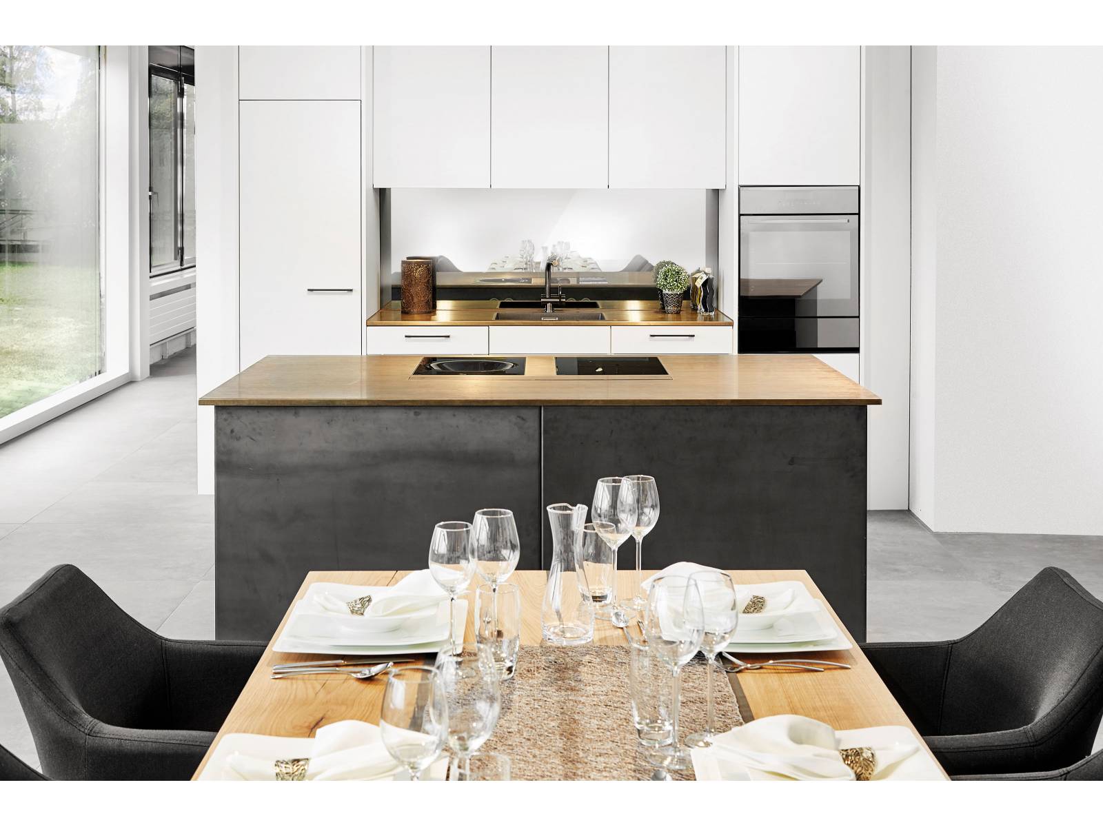 Grosszügig und offen präsentiert sich diese Küche mit der raffinierten Nische, einem Küchenblock als Solitär und Materialien in Dunkel, Hell und Glänzend, die elegant miteinander harmonieren. Sabag.