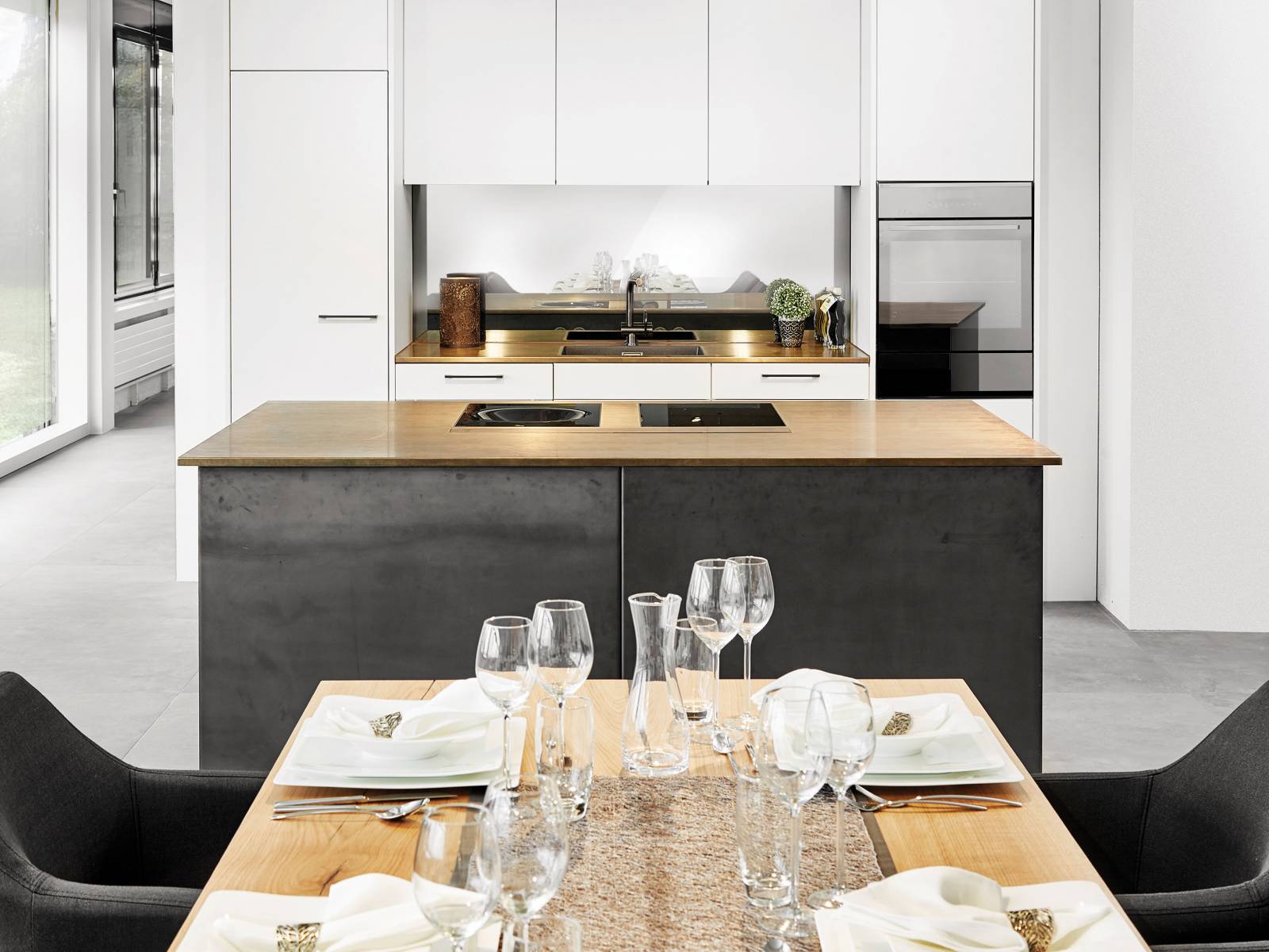 Grosszügig und offen präsentiert sich diese Küche mit der raffinierten Nische, einem Küchenblock als Solitär und Materialien in Dunkel, Hell und Glänzend, die elegant miteinander harmonieren. Sabag.