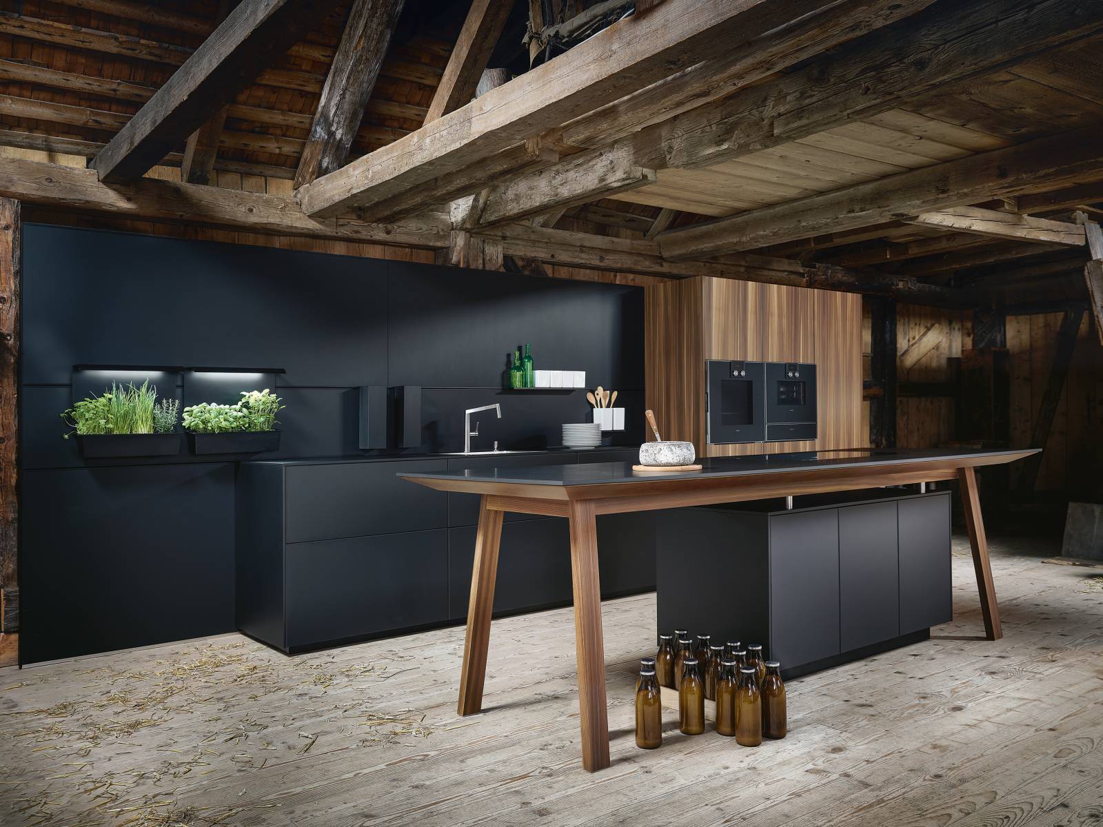 Als Eyecatcher sorgt der zentral platzierte Kochtisch vor allem aufgrund zweier spannender Oberflächenmaterialien, die auch in der restlichen Küche zum Einsatz kommen: Das samtig-schwarze Oberflächenmaterial Fenix mit Anti-Fingerprint-Beschichtung, sowie die markante Erscheinung der Front in Lärche geräuchert, gebürstet. Next 125.