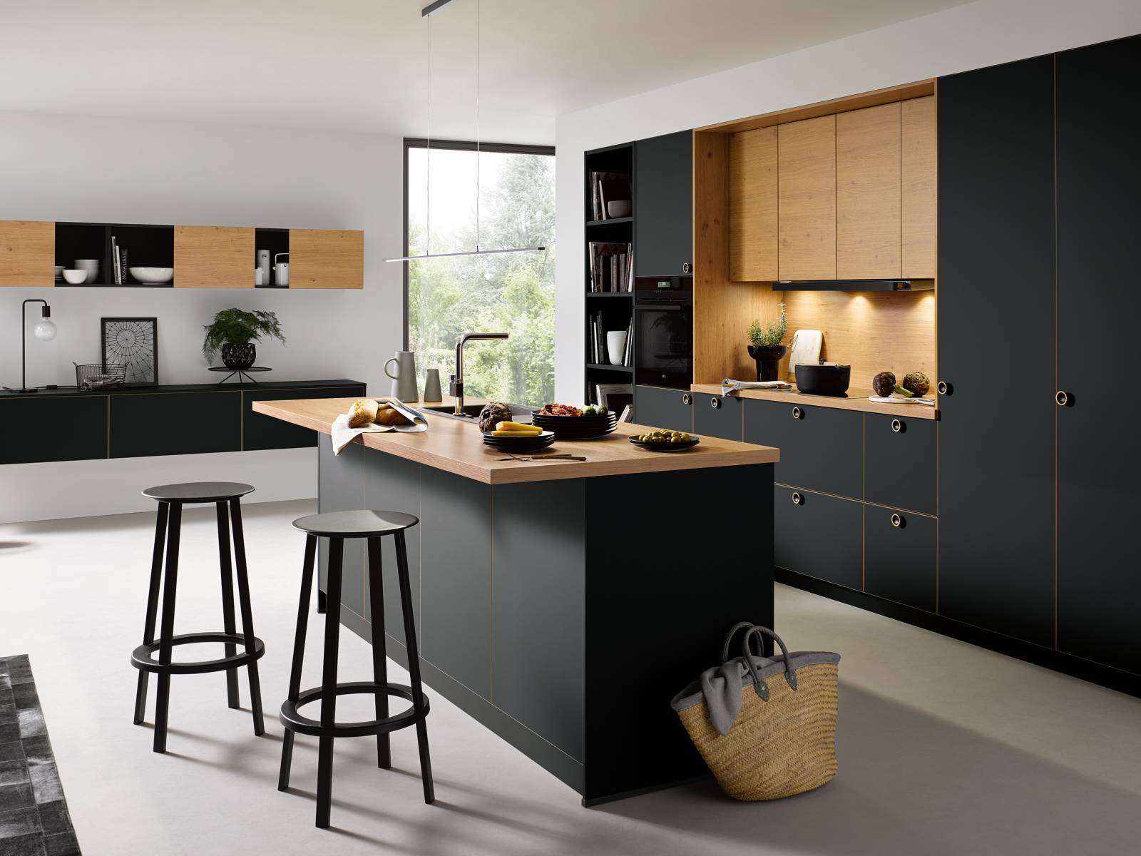 Wie ruhig und behaglich matte Fronten wirken, zeigt der Küchenhersteller mit «Strato matt». Die kühle Eleganz der schwarzen Fronten erhält durch fein abgestimmte Akzente in Holznachbildung die nötige Wärme: Die Holzflächen der Oberschränke wiederholen sich in Dekorkanten und Knopfgriffen und schaffen so eine Verbindung zwischen den gegensätzlichen Materialien. Damit man nicht ständig putzen muss, ist die neue Front mit einer innovativen Anti-Fingerprint-Technologie ausgestattet. Schüller.