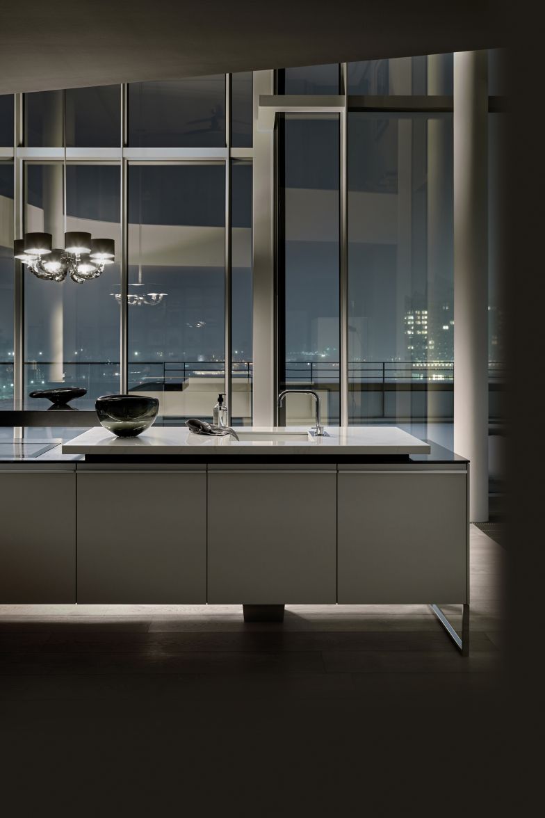 Auf den ersten Blick sieht «+Venovo» aus, als schwebe sie: Zwei Bügel umlaufen den Korpus und heben den Block der länglichen Inselküche über den Boden. Verstärkt wird der Eindruck durch ein spezielles Traggestell, das eine Stütze im Mittelbereich überflüssig macht. Sämtliche Funktionen und Bereiche wie Kochfeld, Absaugung, Backofen, Kühlgerät, Spüle und Arbeitsfläche sind unauffällig integriert. Im klaren Ordnungssystem der Schubladen lassen sich Besteck, Gewürze oder andere Küchenutensilien sicher verstauen. Pggenpohl.