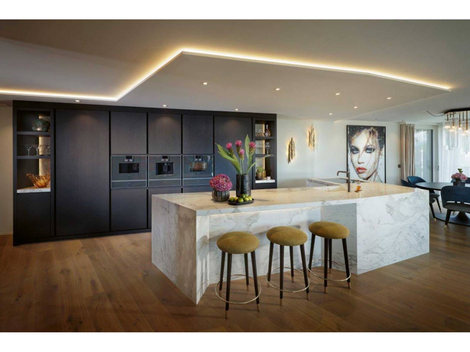 Alles andere als Standard ist dieser Küchen­umbau hier, der vom Entwurf über die Planung bis hin zur Fertigung und Montage aus einer Hand stammt. Auffallend ist unter anderem die asymmetrisch geformte Insel aus hellem Marmor mit integriertem Sitzbereich, die einen schönen Kontrast zur raumhohen Küchenzeile aus gebürsteter, schwarz gebeizter Eiche bildet. ZBÄREN.