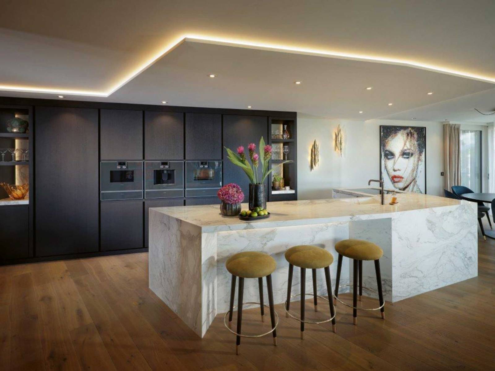 Alles andere als Standard ist dieser Küchen­umbau hier, der vom Entwurf über die Planung bis hin zur Fertigung und Montage aus einer Hand stammt. Auffallend ist unter anderem die asymmetrisch geformte Insel aus hellem Marmor mit integriertem Sitzbereich, die einen schönen Kontrast zur raumhohen Küchenzeile aus gebürsteter, schwarz gebeizter Eiche bildet. ZBÄREN.